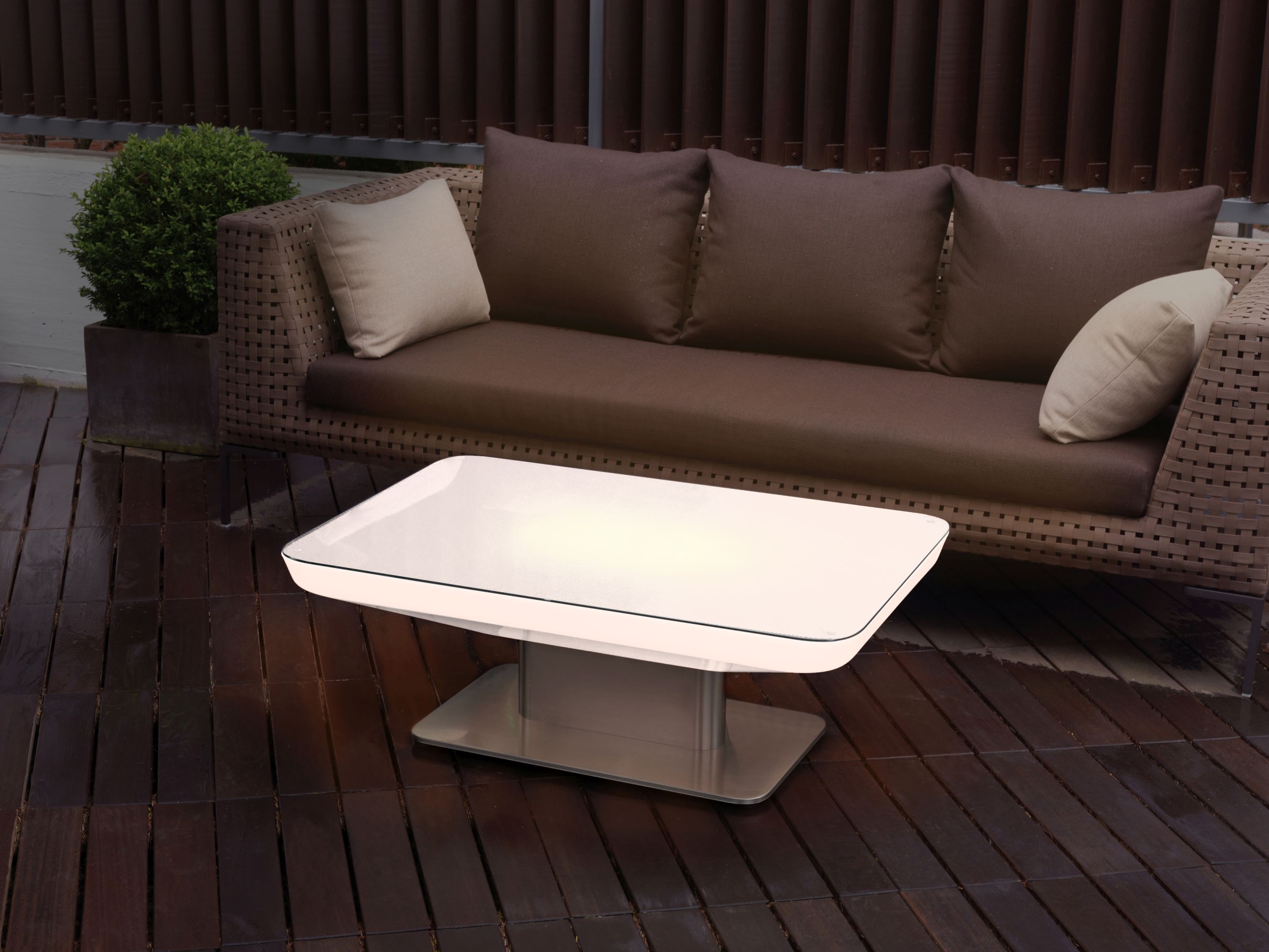 Studio 45 Outdoor Tisch von Moree mit Glasplatte und Sofa auf einer Holzterrasse.