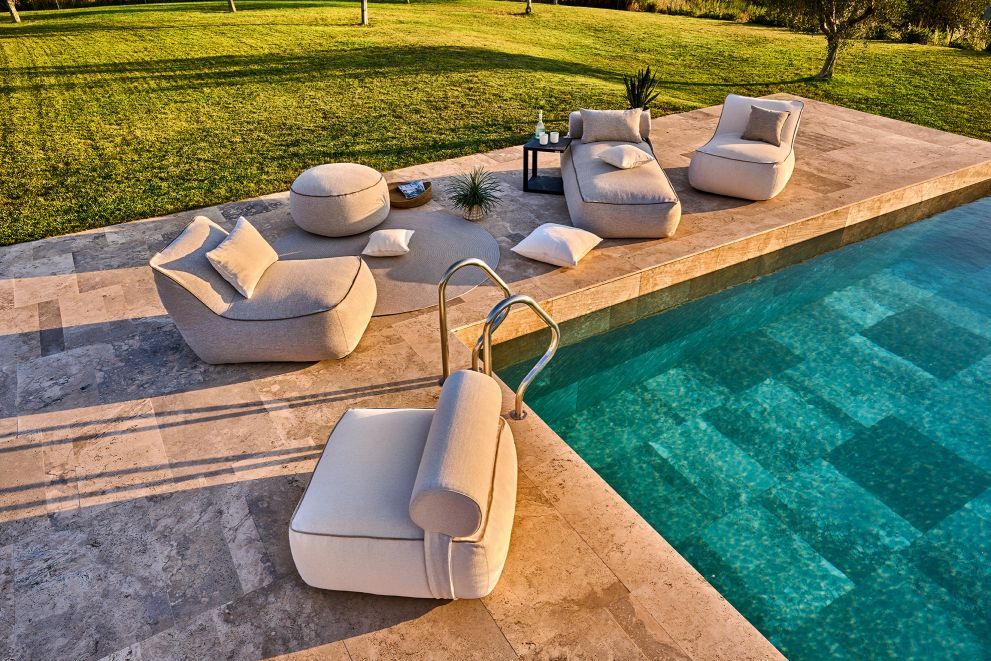 Luxuriöse Outdoor-Lounge-Möbel aus Stoff am Pool, bestehend aus Sesseln, Liege und Pouf.