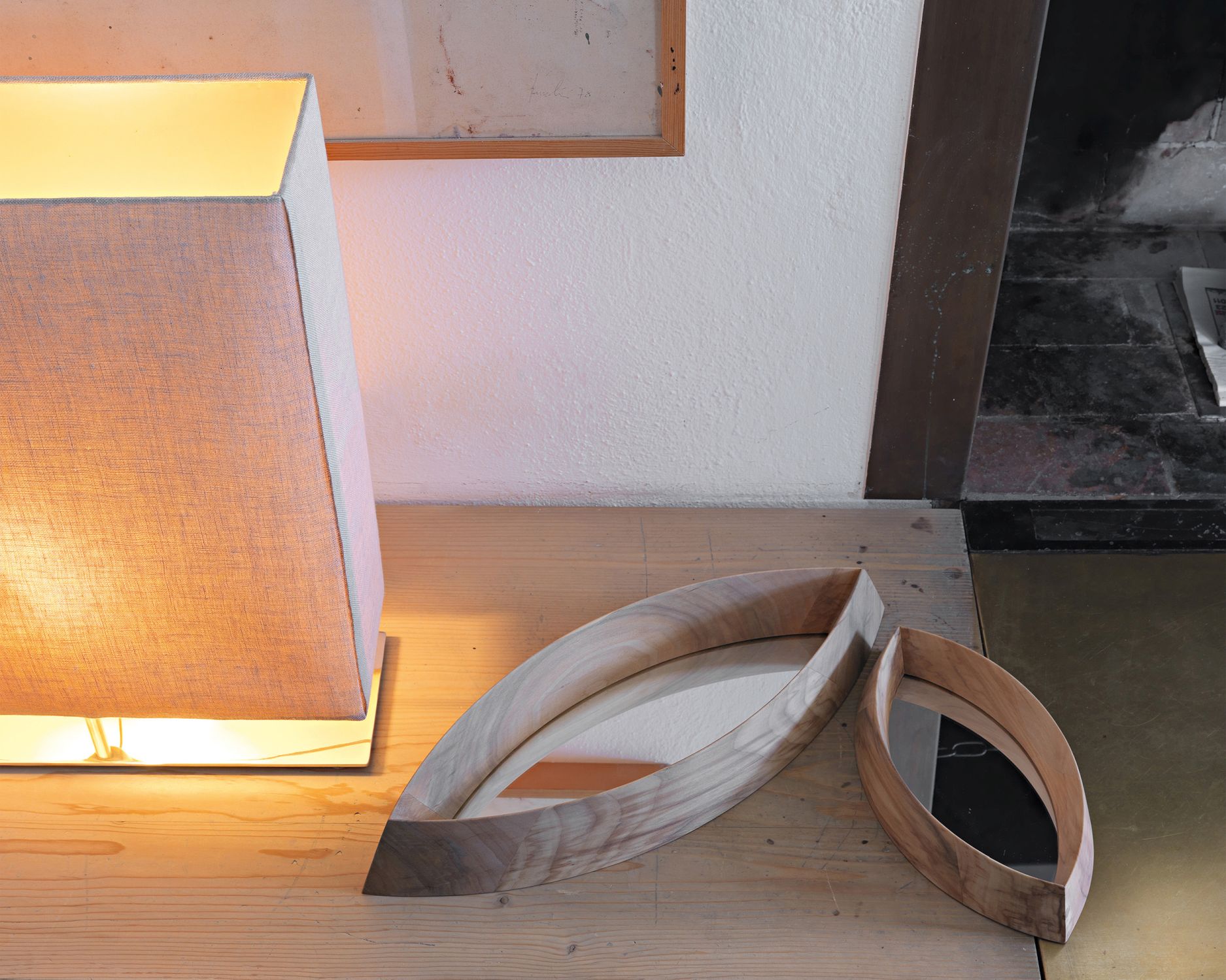 Zwei Mamanonmama Spiegel mit Holzrahmen in Blattform auf einem Holztisch, neben einer Lampe.