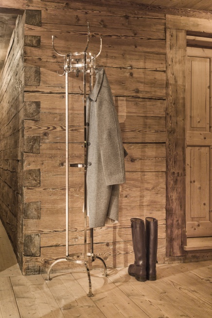 Nymphenburg Garderobenständer von ClassiCon in Schwarz mit Mantel und Stiefeln vor Holzwand.