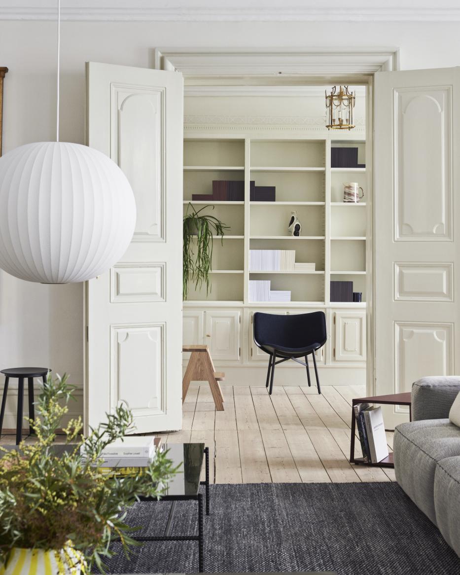 Wohnzimmer Interieur mit Hay Butler Hocker, schwarzem Stuhl und Holzhocker im Hintergrund. Moderner Hocker für stilvolles Wohnen.