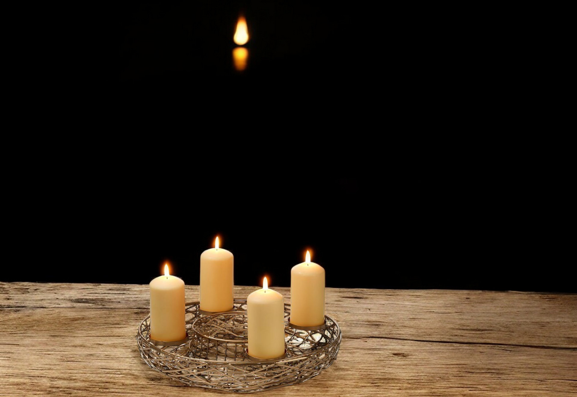 Adventskranz mit vier brennenden Kerzen auf rustikalem Holzuntergrund, stilvolles Einzelstück von Philippi.