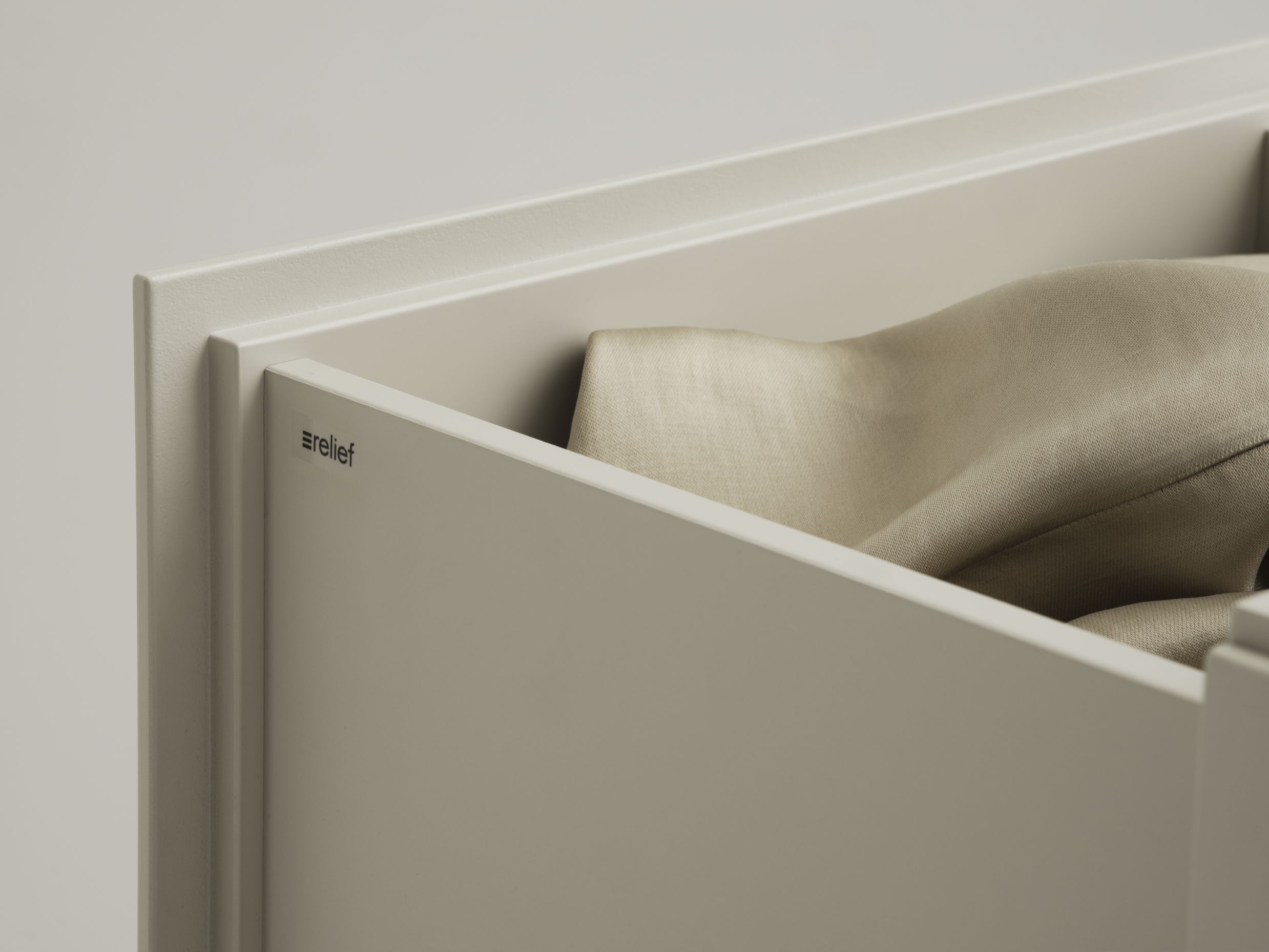 Detailaufnahme einer offenen Relief Kommode von String Furniture mit Textilien.