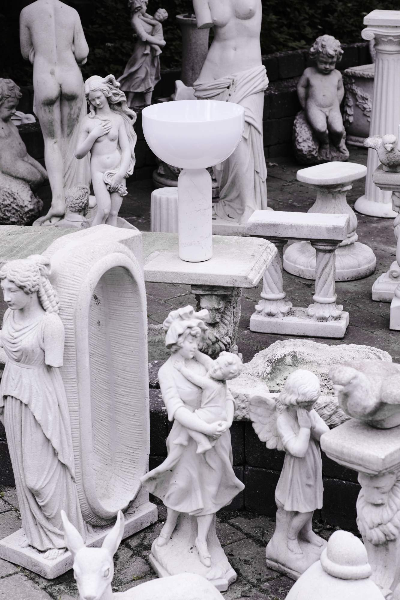 New Works Kizu Tischleuchte in Weiß, umgeben von Statuen. Moderne Lampe für stilvolle Innenbeleuchtung.