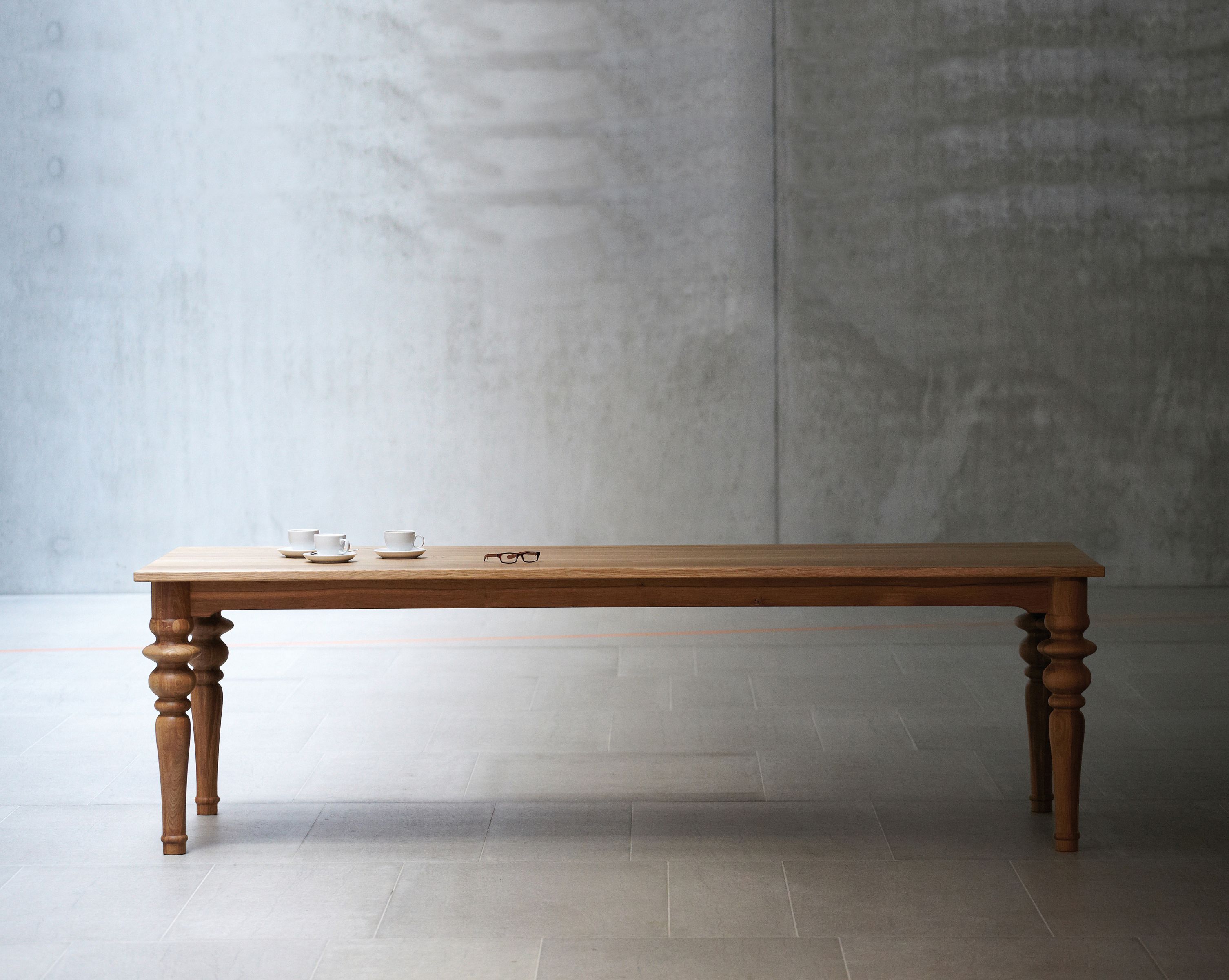 Drexler Tisch von Jan Kurtz: Langer Holztisch mit gedrechselten Beinen, Kaffeetassen und Brille.