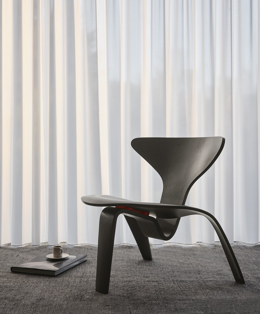 Schwarzer PK0 A™ Chair Stuhl von Fritz Hansen vor weißem Vorhang, modernes Möbeldesign.