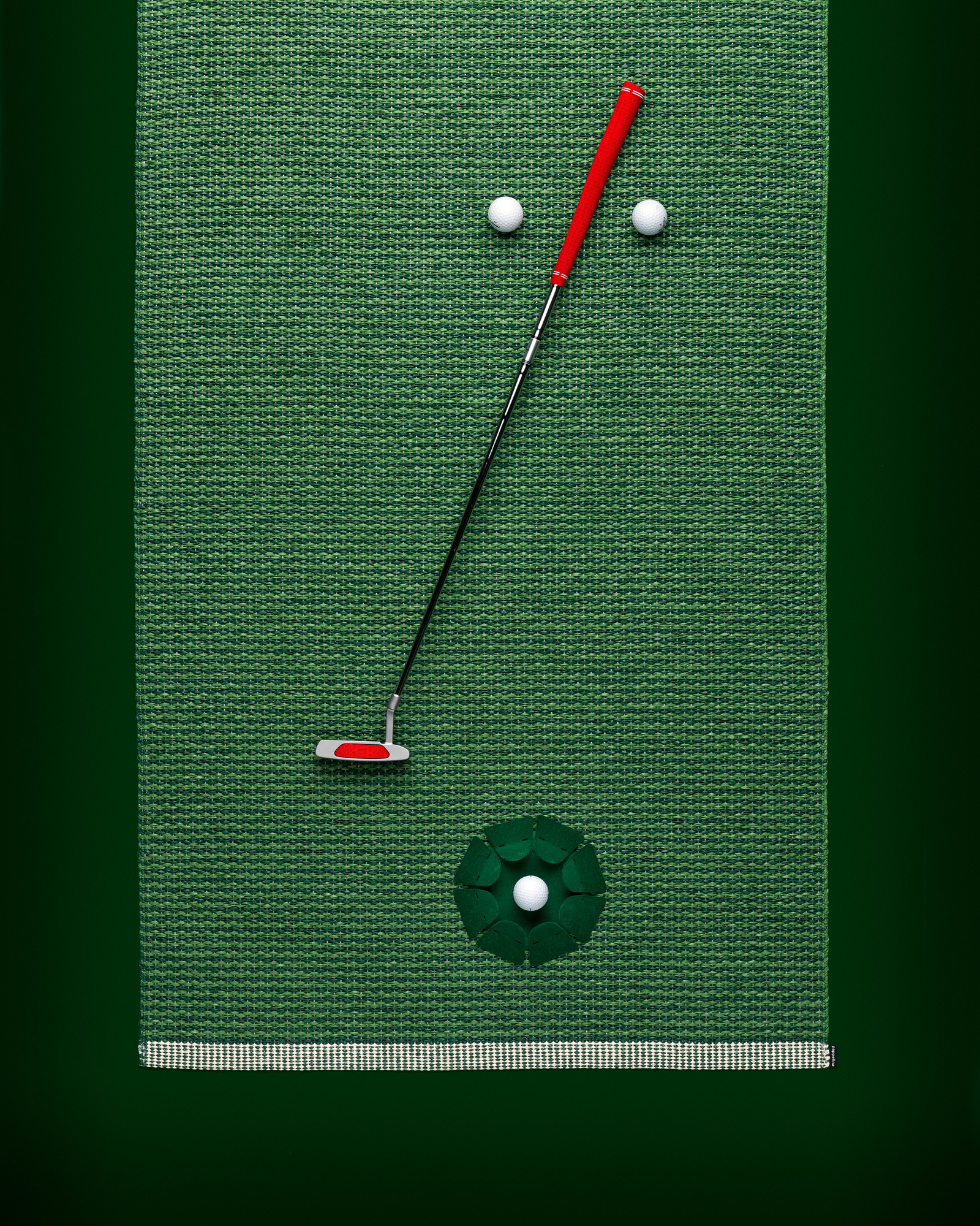 Grüner Mono Kunststoffteppich von Pappelina, 60x150 cm, mit Golfschläger und Golfbällen als Dekoration.