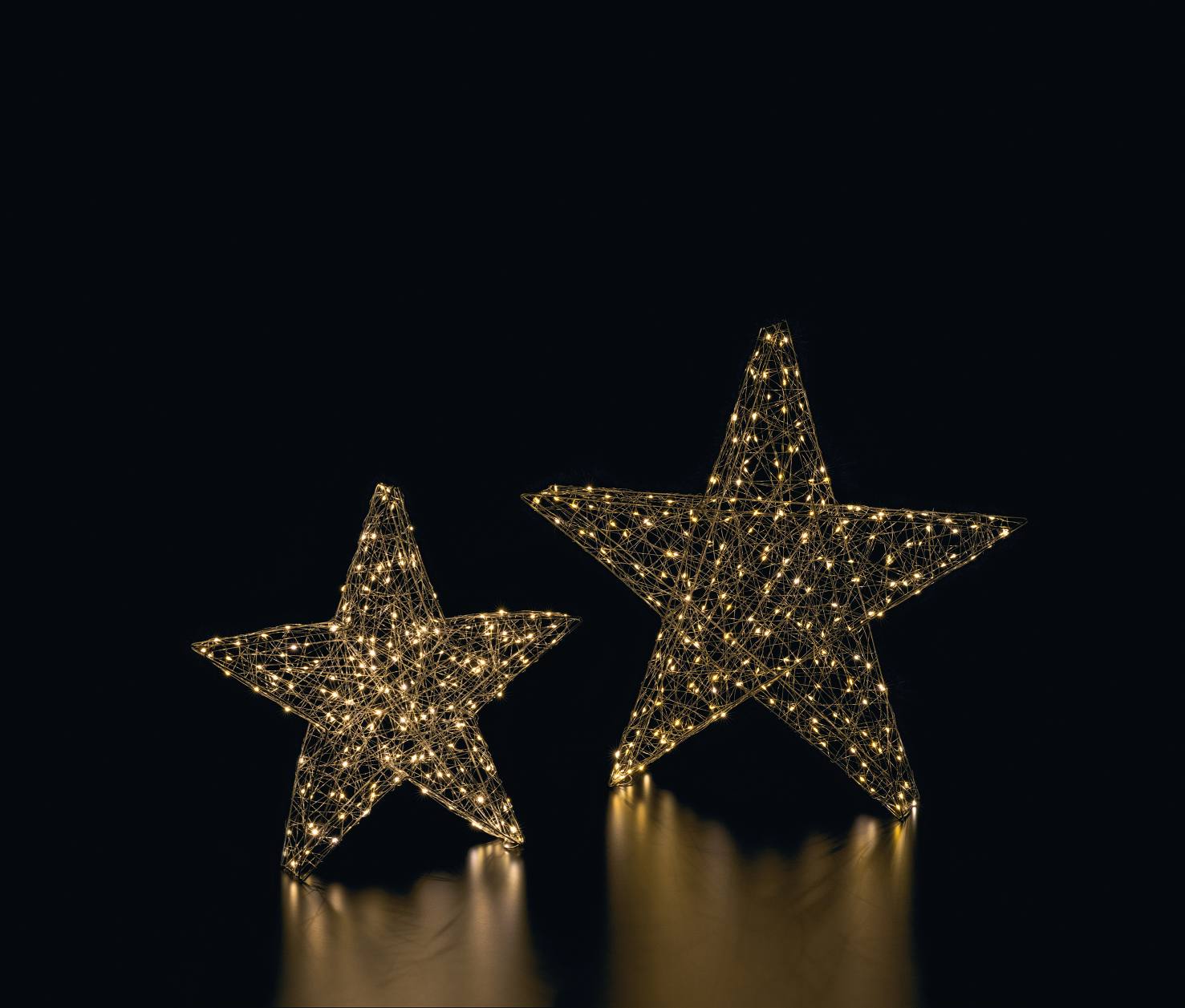 Zwei leuchtende Matar LED Sterne als Weihnachtsdeko, warmweißes Licht auf schwarzem Hintergrund.