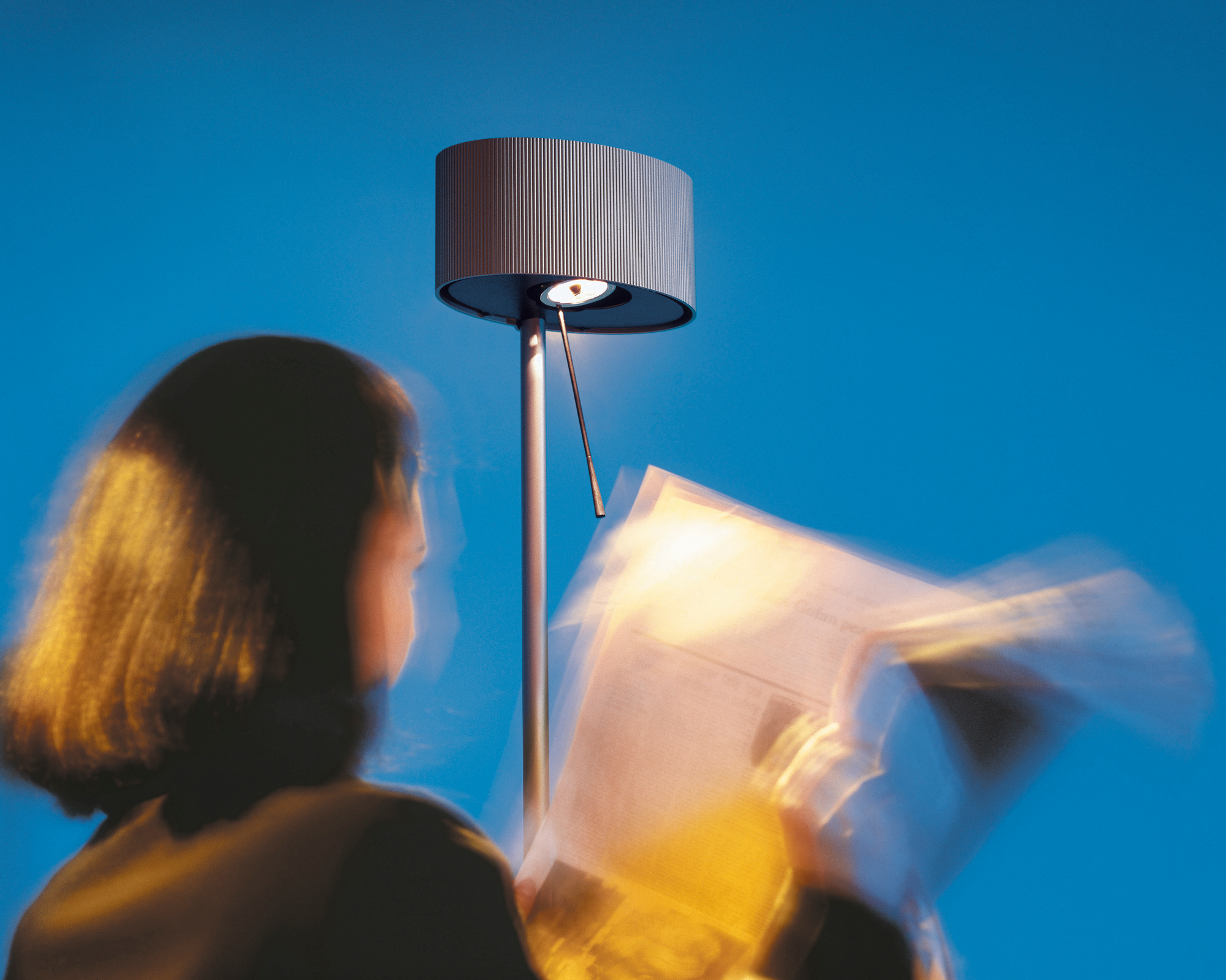 Diogenes LED Stehleuchte von Belux in Goldgrau beim Lesen einer Zeitung. Design Stehlampe.