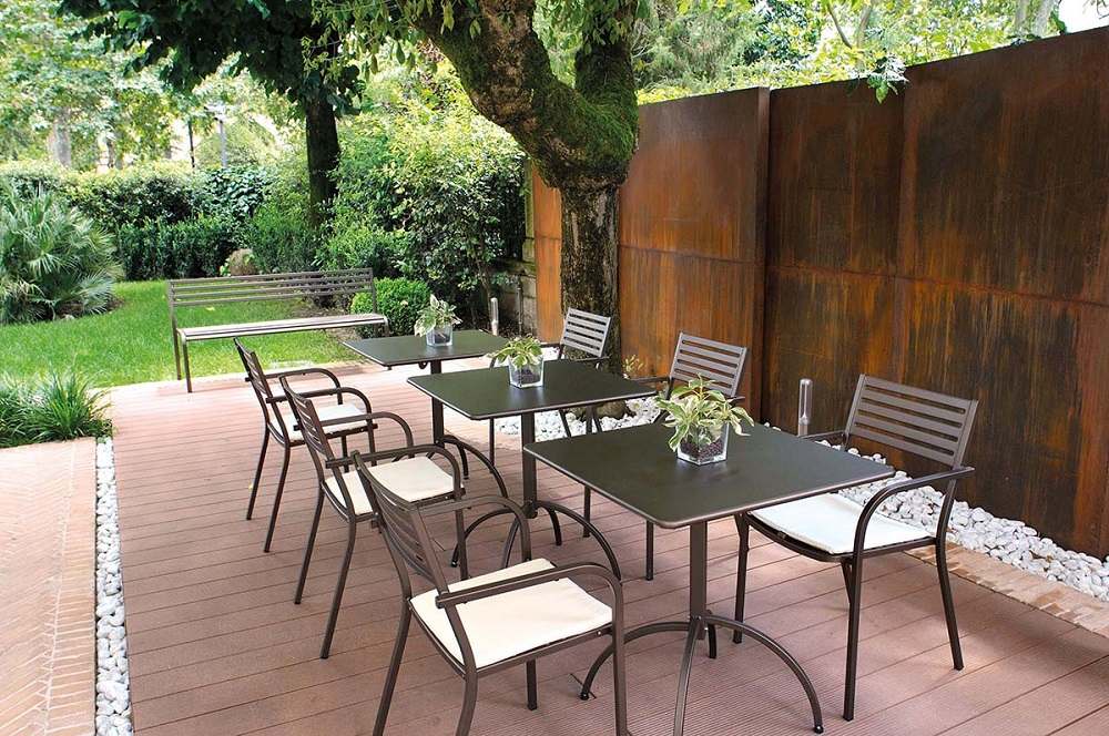 Schwarzer Segno Armchair Armlehnstuhl von Emu auf einer Terrasse mit Tischen und Gartenmöbeln.