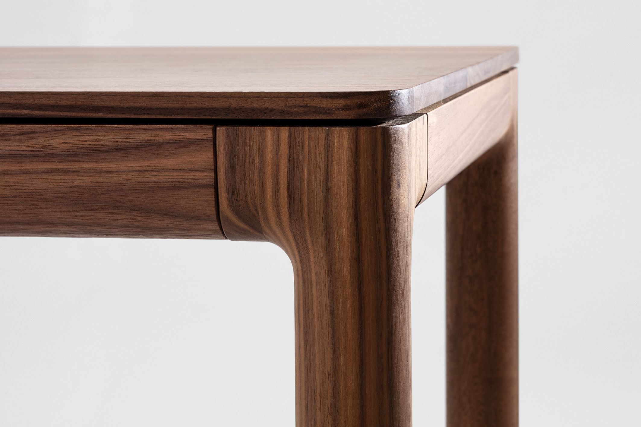 Detailaufnahme des M11 Tischs: Massivholz Tischplatte und Bein aus edlem Nussbaumholz.