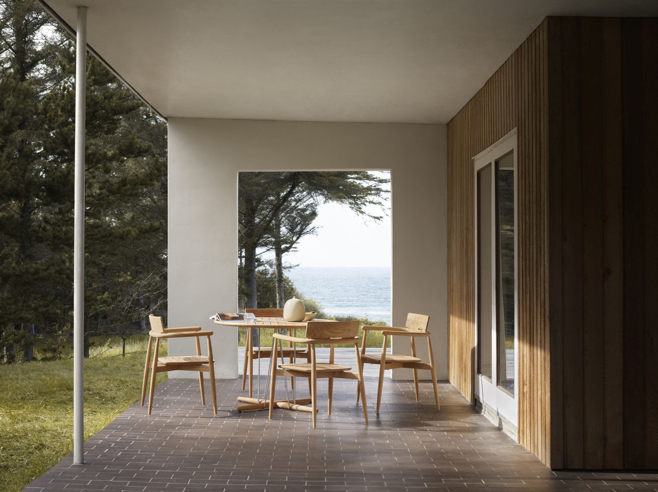 E008 Embrace Outdoor Stuhl von Carl Hansen & Søn an Esstisch auf Terrasse.