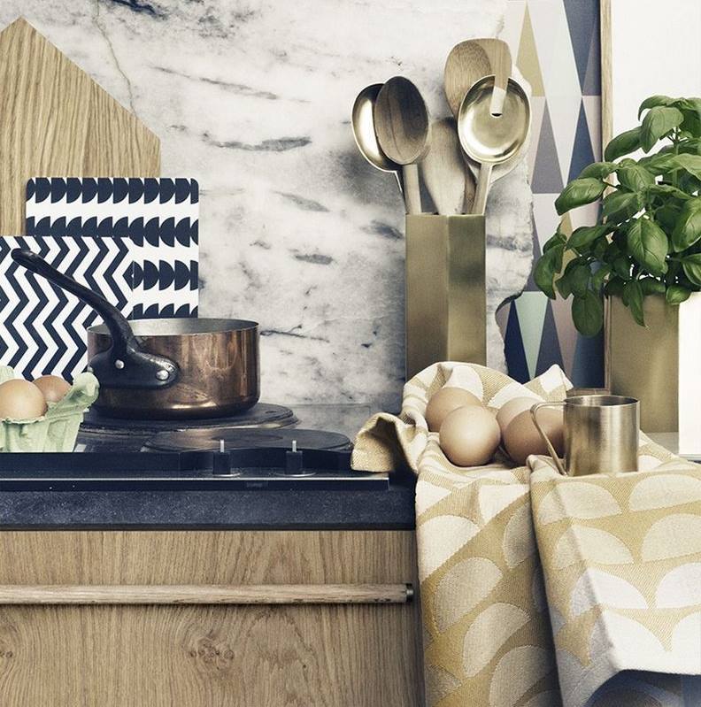 Küchenstillleben mit goldenem Salatbesteck, Kochtopf, Eiern und Basilikum vor Marmorwand. Ferm Living inspiriert.