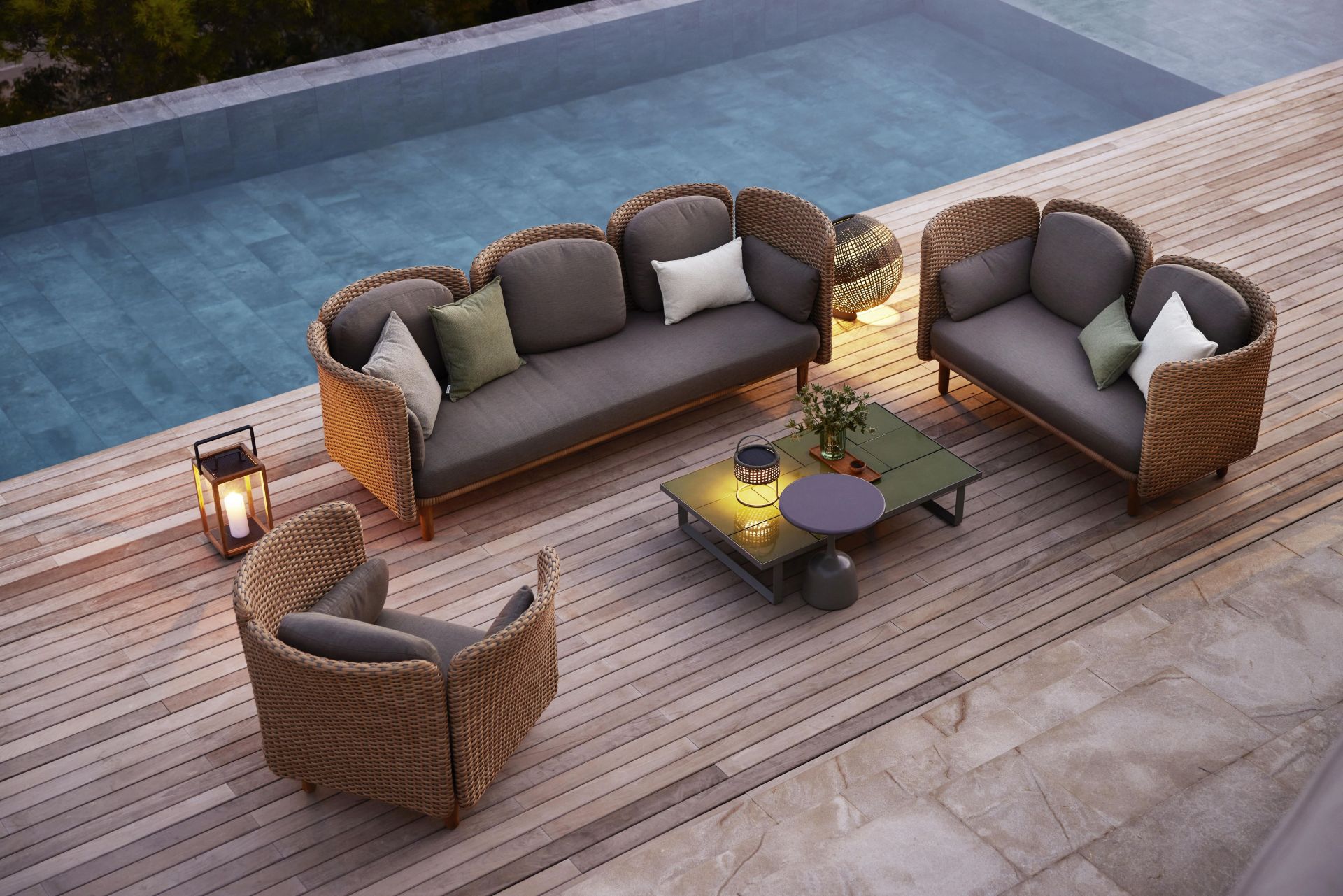 Luxuriöses Gartenmöbel-Set aus Rattan mit Sofa, Sessel und Tisch am Pool für entspannte Stunden.