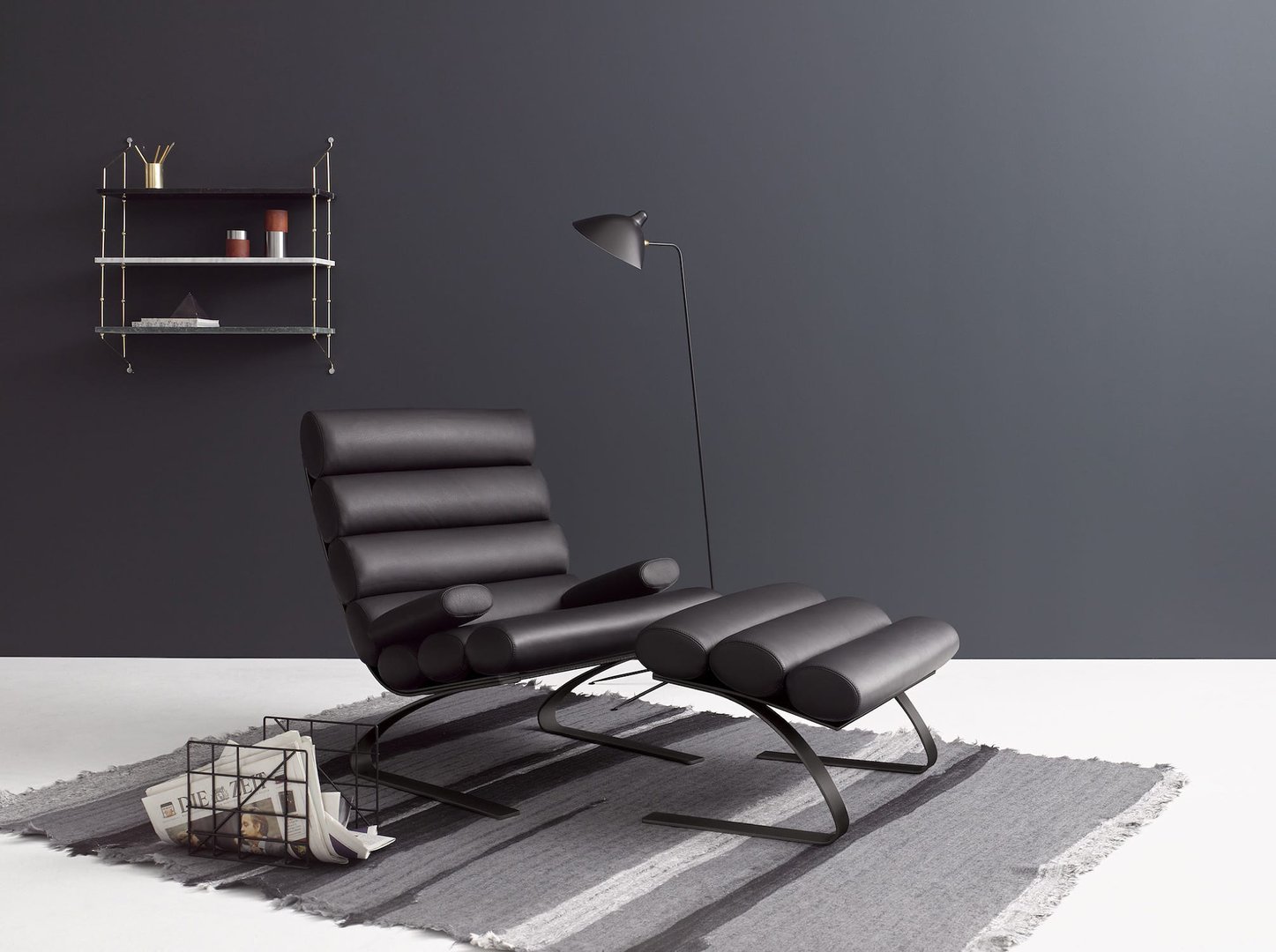 Schwarzer Cor Hocker aus Leder mit Fußhocker auf grauem Teppich, modernes Möbeldesign für Wohnzimmer.