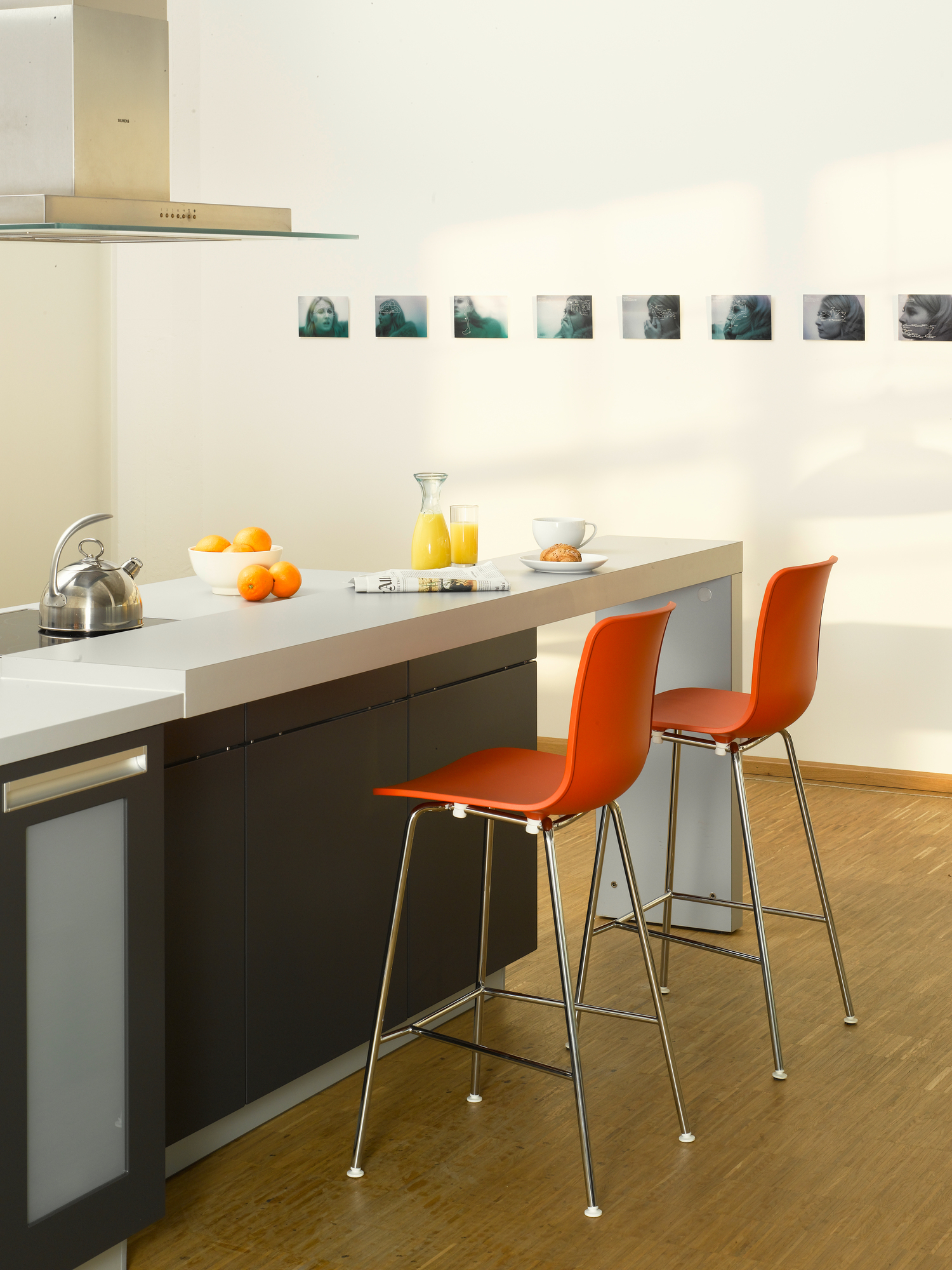 Zwei orangefarbene Hal Stool Barhocker von Vitra an einer Küchentheke mit Frühstück.