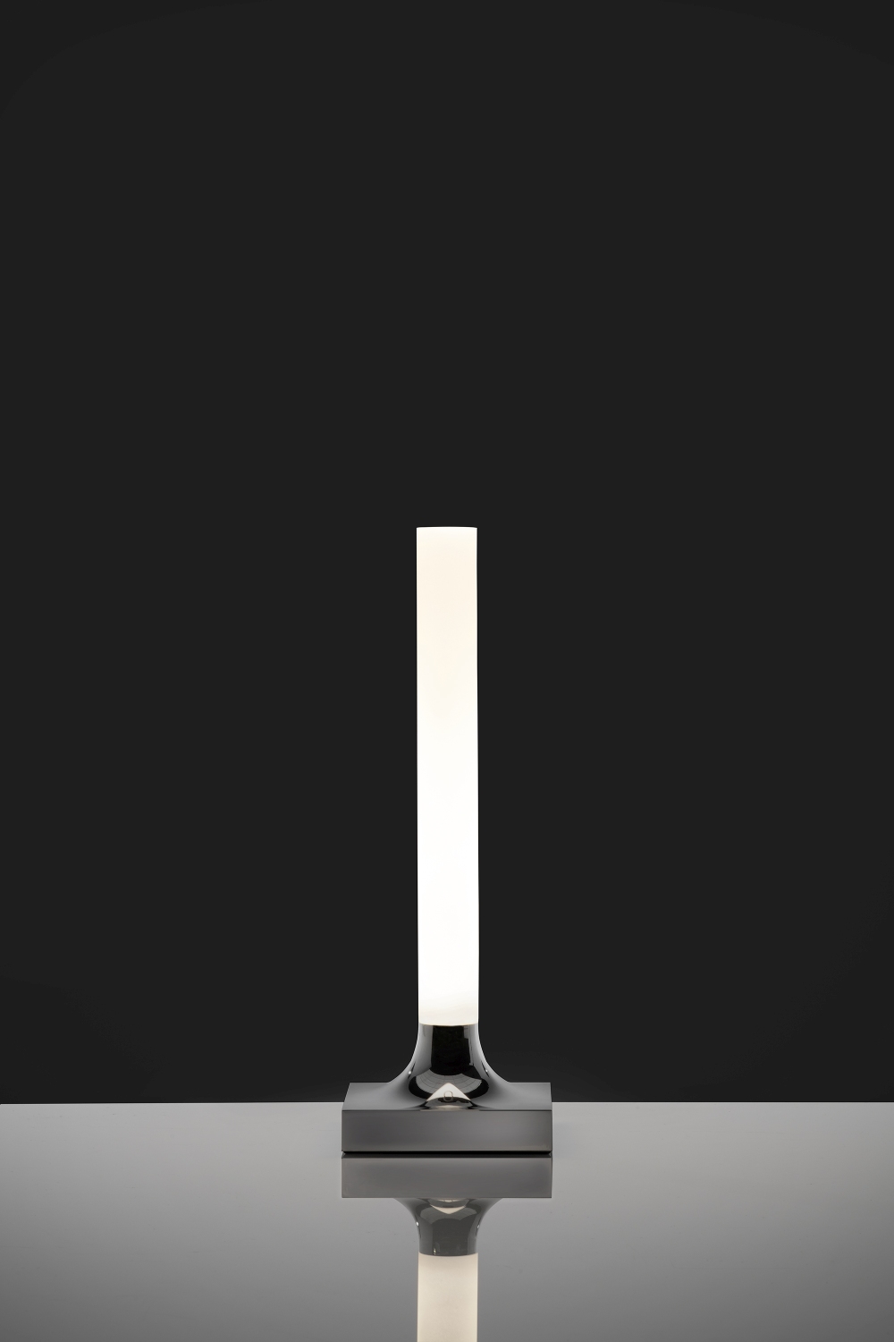 Goodnight Akkuleuchte von Kartell, verchromt und poliert, mit LED-Lichtstab auf glänzendem Untergrund.