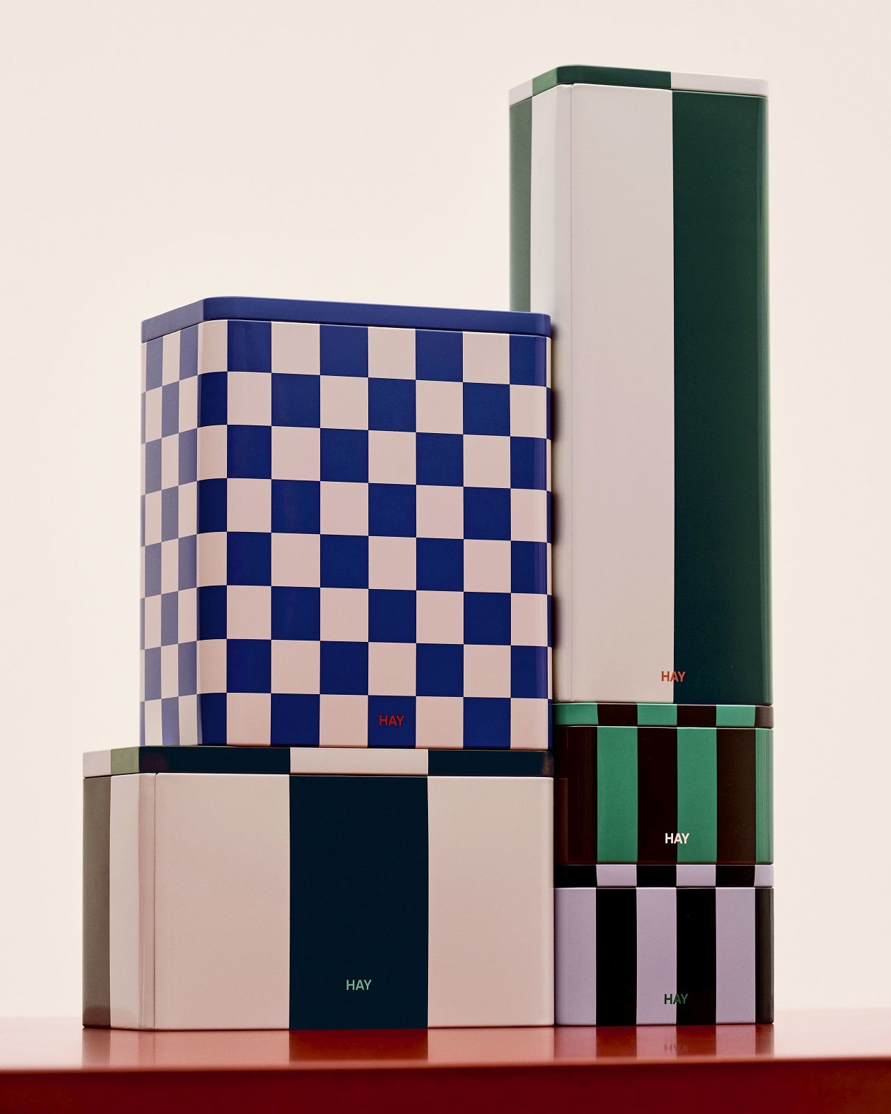 Gestapelte Hay Aufbewahrungsboxen aus Metall in verschiedenen Farben und Mustern, inklusive blau karierter Dose.