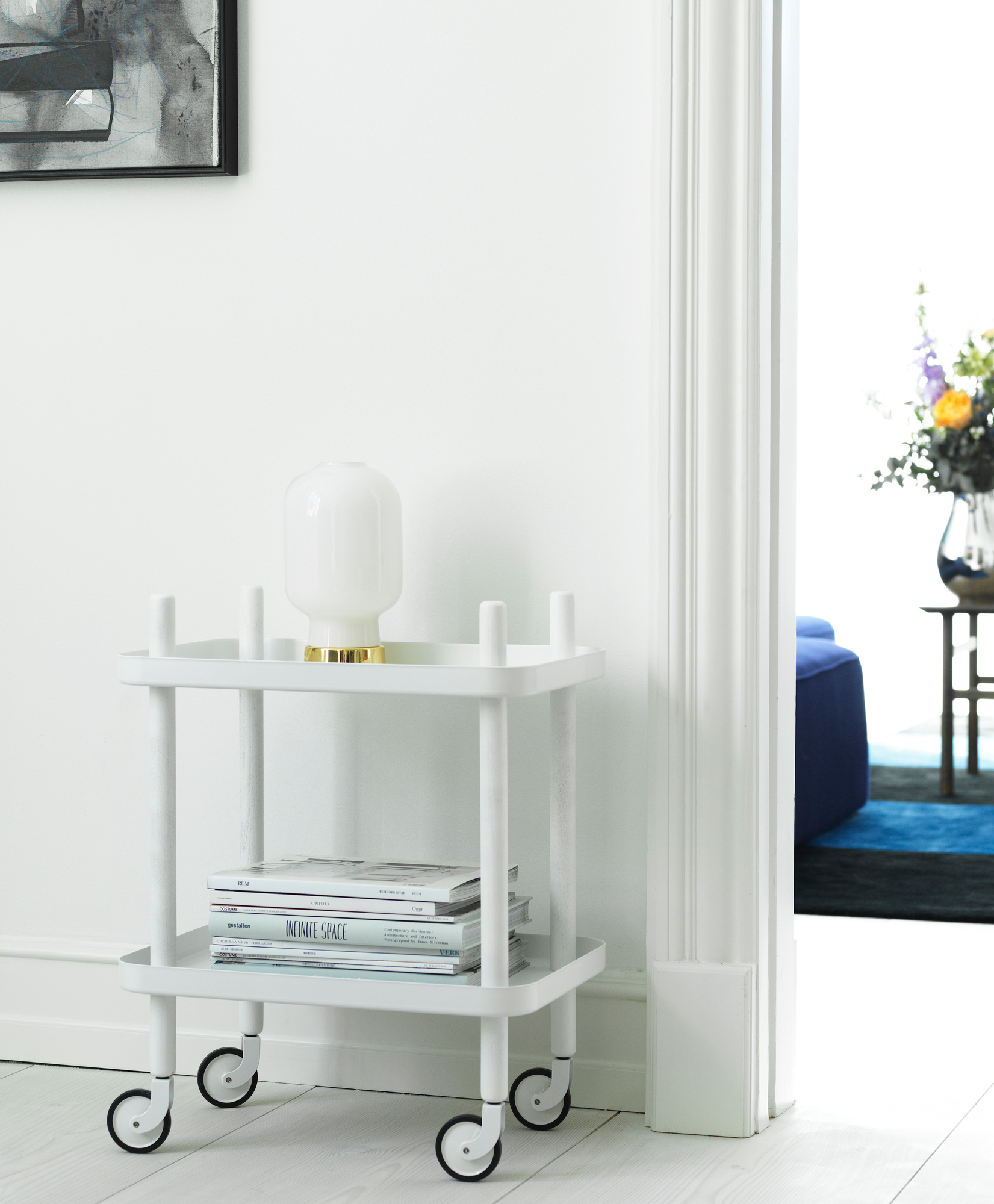 Weißer Normann Copenhagen Block Table Servierwagen mit Lampe und Magazinen im hellen Raum.