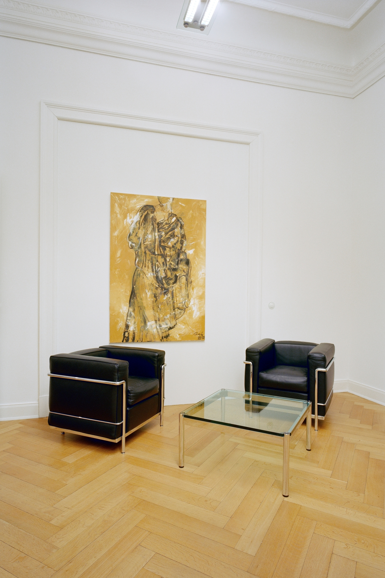 USM Haller Tisch quadratisch mit Glasplatte, kombiniert mit schwarzen Ledersesseln und Kunstwerk im minimalistischen Wohnzimmer.