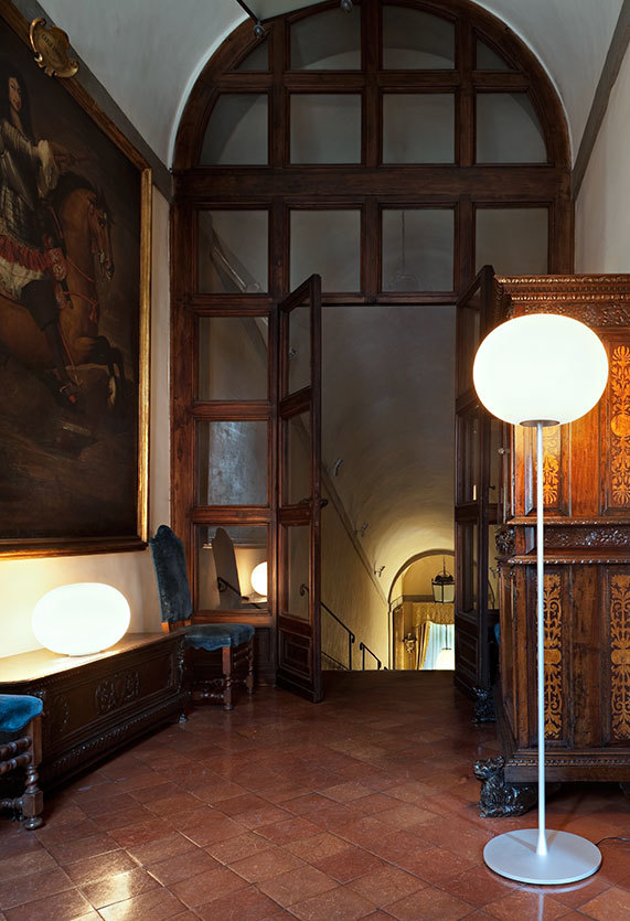 Glo Ball Stehleuchte von Flos in einem historischen Raum mit Kunst und Treppe.