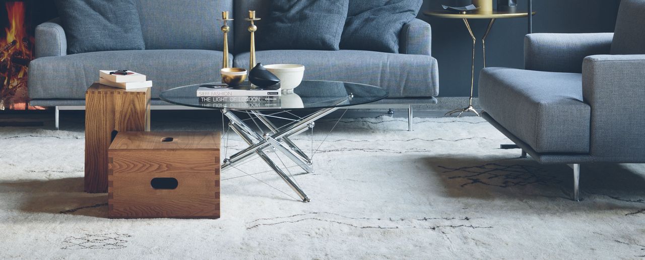 LC14 Tabouret Hocker aus Holz neben Sofa und Couchtisch im modernen Wohnzimmer.