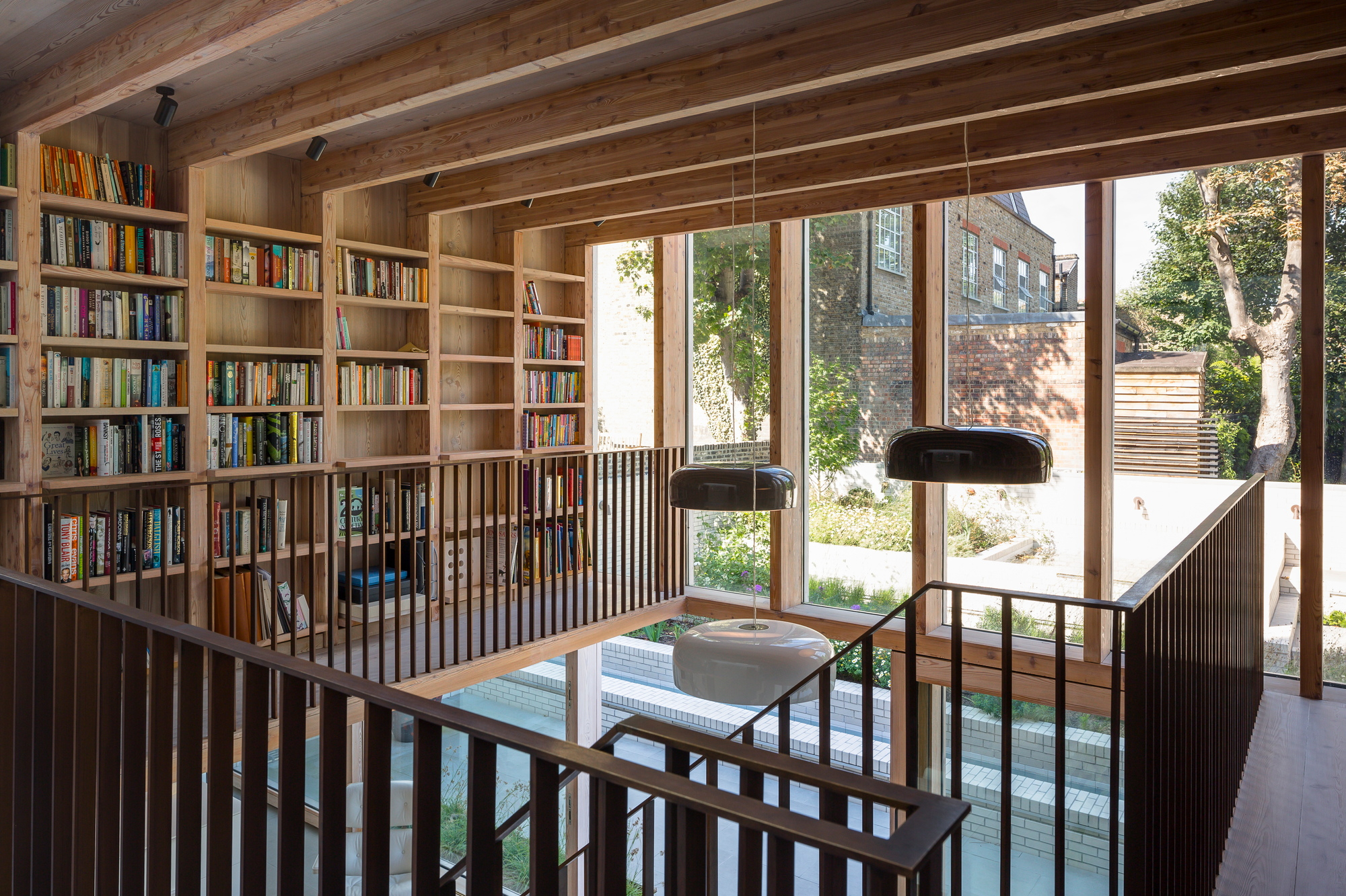 Innenaufnahme mit Smithfield Pendelleuchten von Flos in modernem Wohnraum mit Bücherregal.