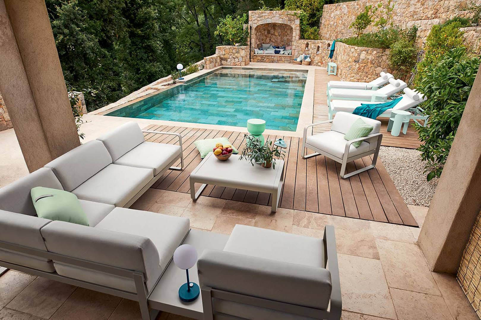 Luxuriöse Gartenmöbel-Lounge am Pool: Weiße Outdoor-Sofas, Sessel und Liegen für entspanntes Sommer-Ambiente.