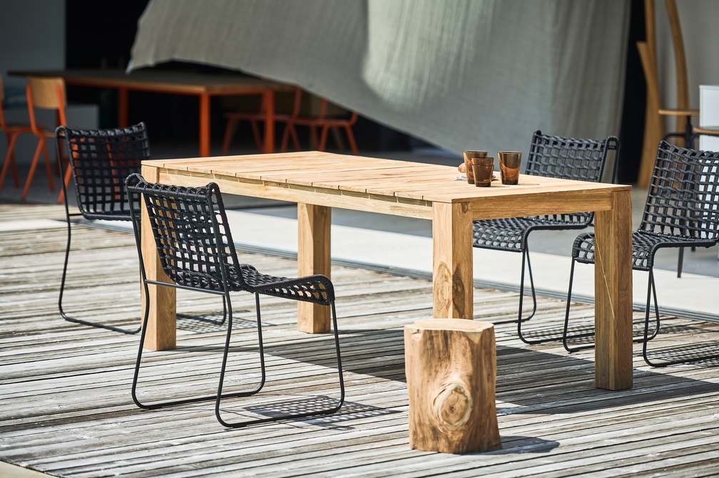 Jan Kurtz In/Out Stühle mit Outdoor-Tisch und Hocker aus Holz auf einer Terrasse.