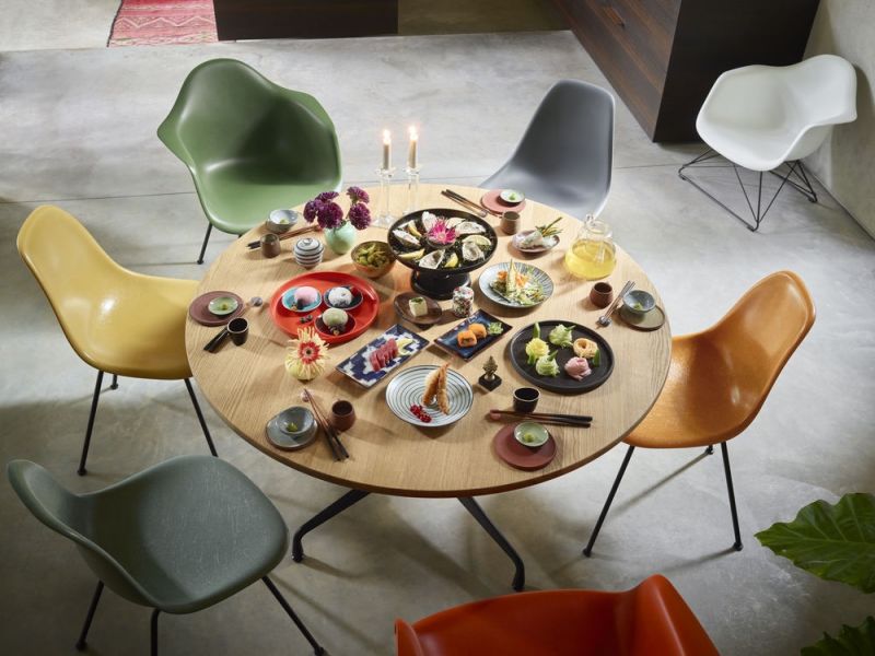 Esstisch mit Sushi und japanischen Speisen umgeben von bunten Designerstühlen, Eames Plastic Chairs.