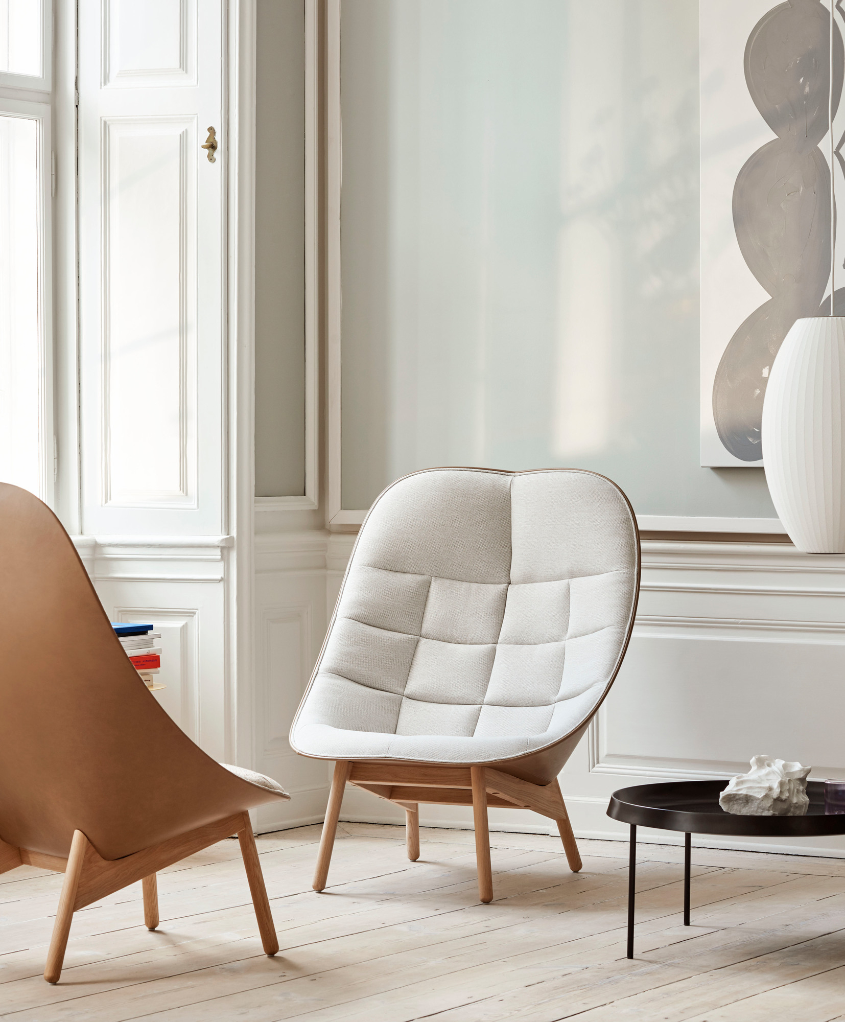 Zwei moderne Sessel mit Holzbeinen und gepolsterten Sitzen in heller Inneneinrichtung.