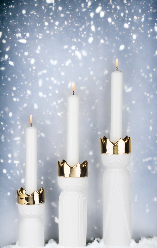 Königslicht Kerzenständer 3er Set Räder: Drei weiße Kerzenleuchter mit goldenen Kronen und brennenden Kerzen.