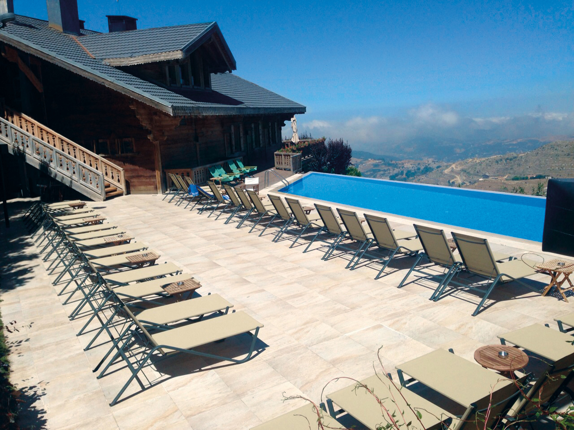 Reihe von Emu Holly Sonnenliegen am Pool mit Panoramablick, ideal für Entspannung im Freien.