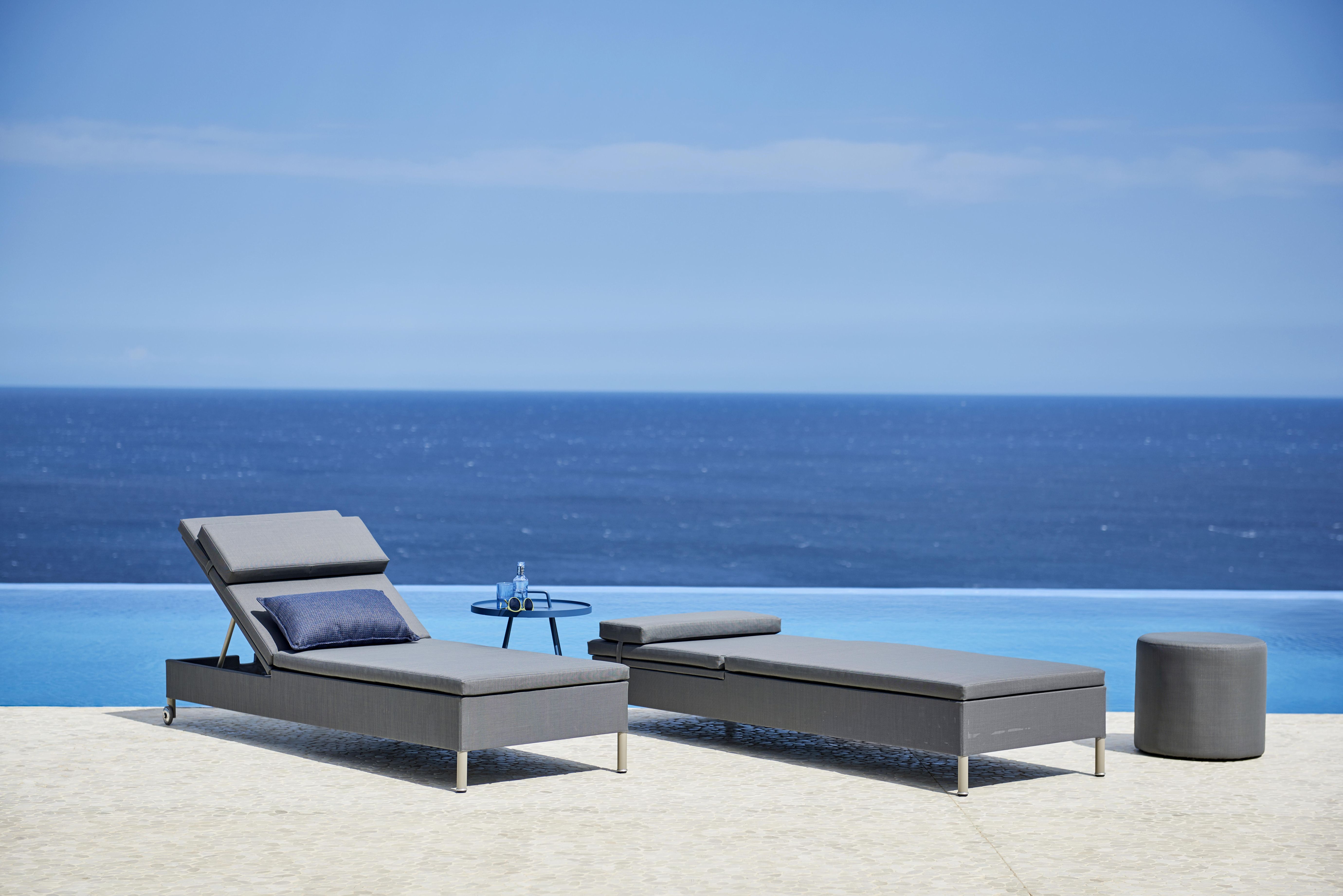 Cane-Line Rest Sonnenliege für zwei Personen mit grauem Bezug und Meerblick.
