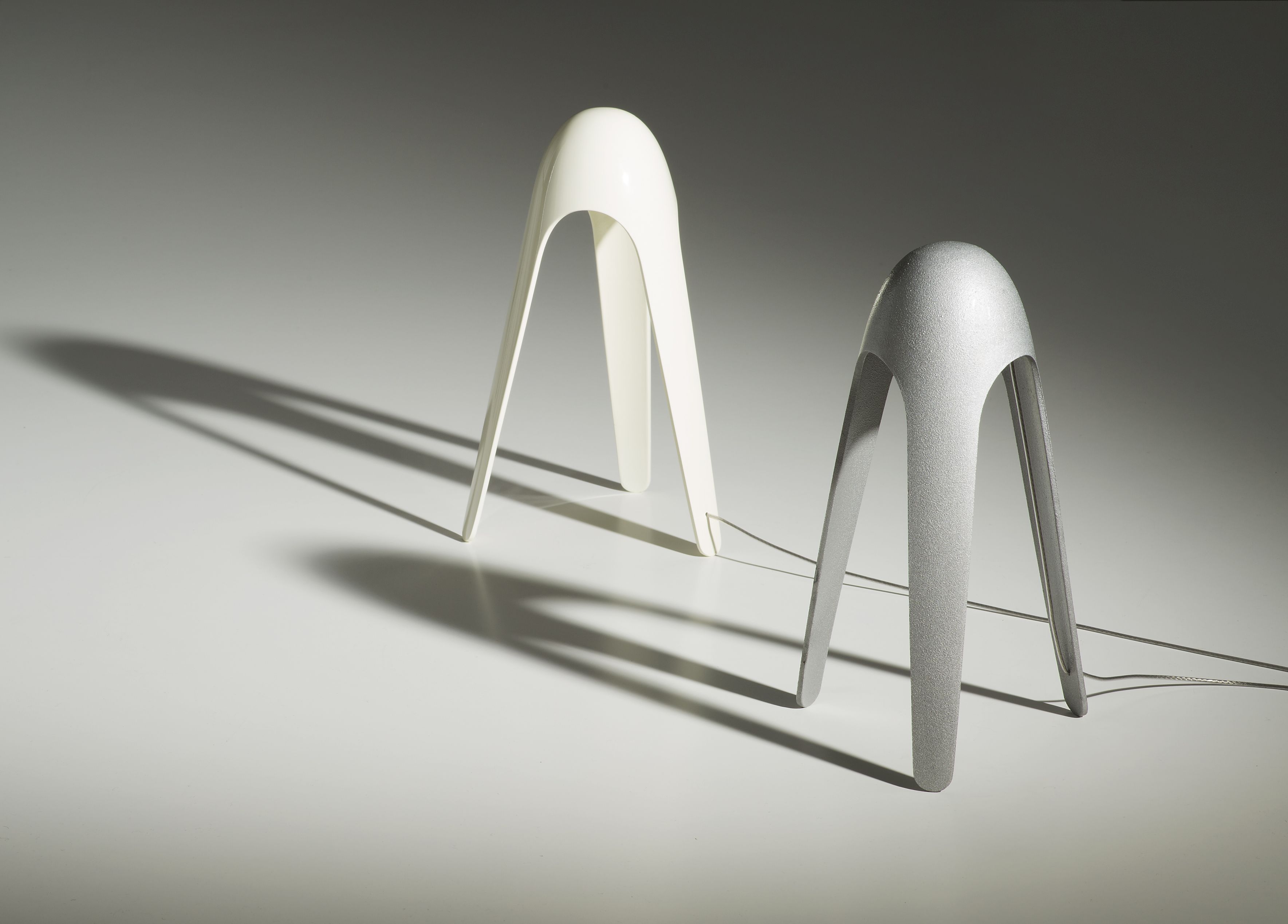 Zwei Cyborg Tischleuchten von Martinelli Luce in Weiß und Silber auf hellem Untergrund.