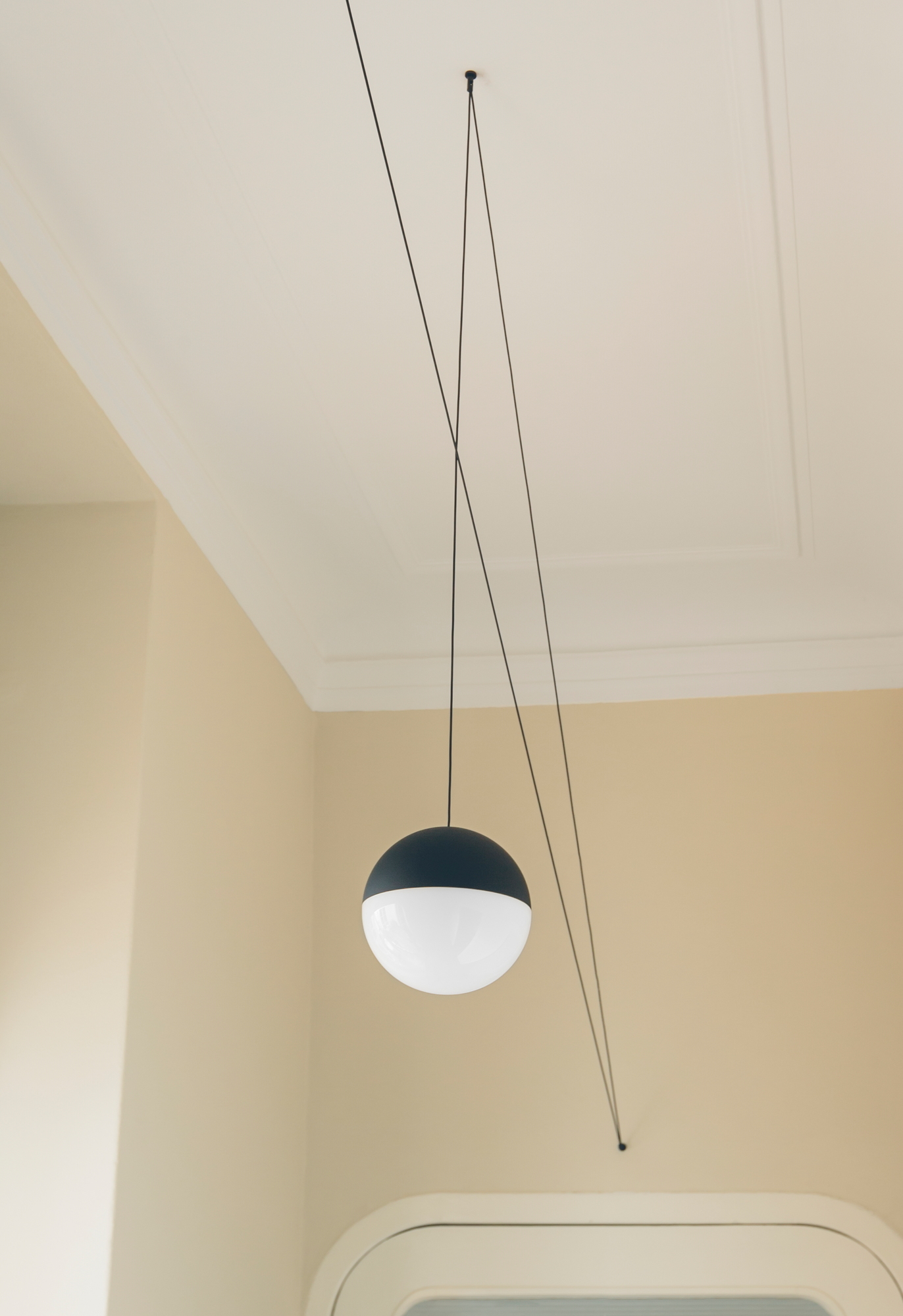 Nahaufnahme der String Light Kugelkopf Pendelleuchte von Flos mit schwarzem Kabel.