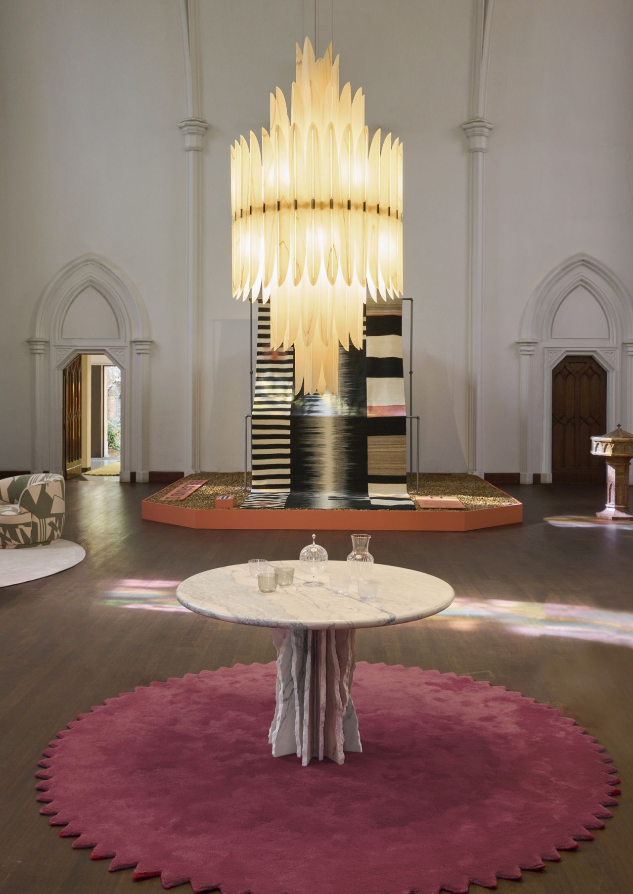 Innenaufnahme mit der Voliere Pendelleuchte von LZF Lamps, Tisch mit Gläsern und Teppichen.