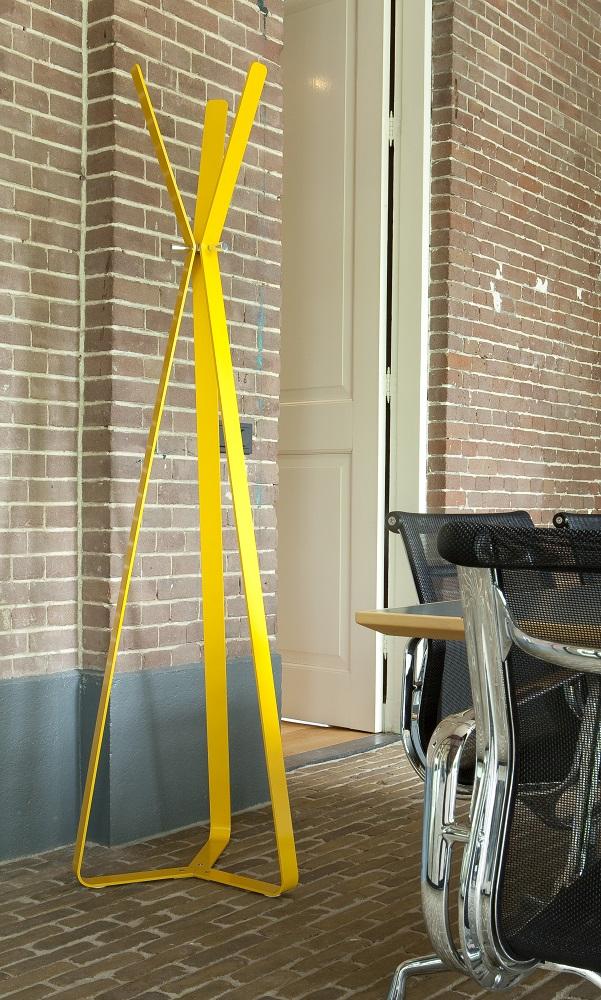 Gelbe Bend Standgarderobe von Cascando vor Backsteinwand, moderne Garderobenlösung für Büro und Zuhause.