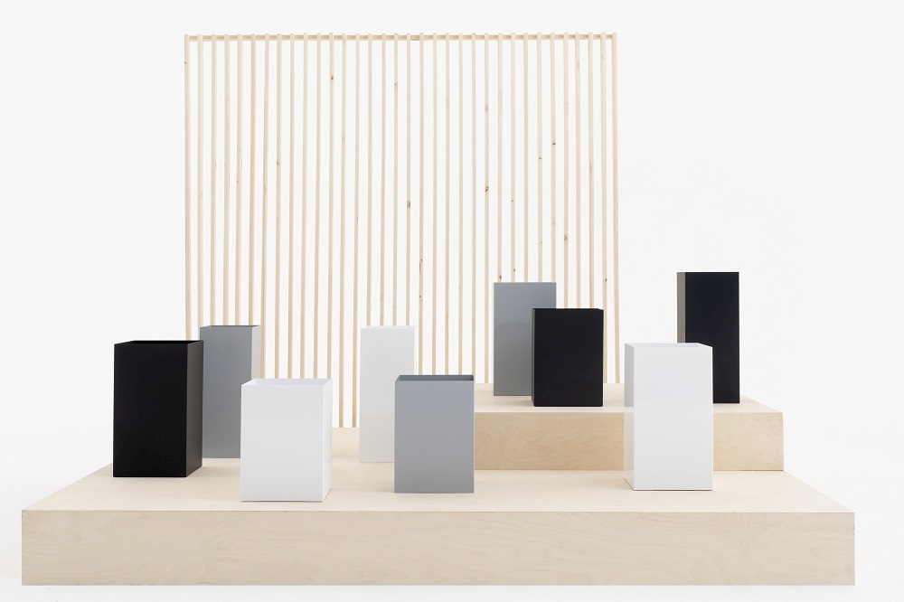 Quadratische Cascando Papierkörbe in Schwarz, Weiß und Grau auf einer Holzplattform. Design Papierkorb.