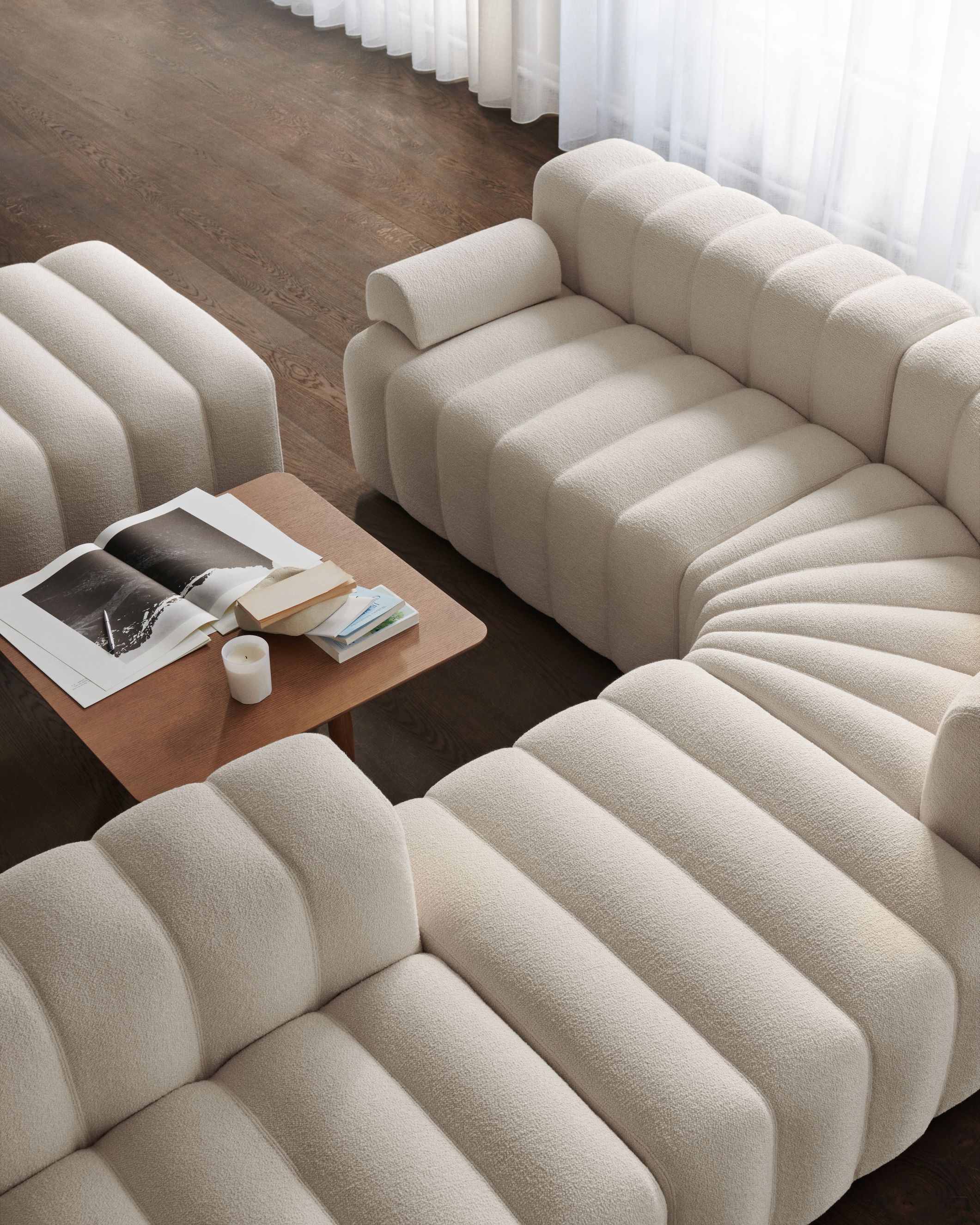 Oku Couchtisch Eiche hell geräuchert von Norr11 neben einem modularen Sofa in hellem Bouclé.