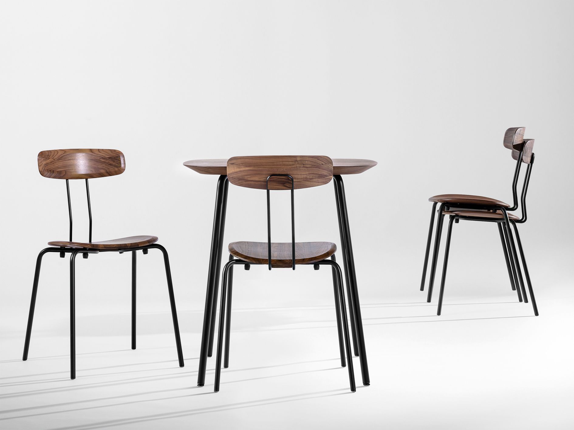 Okito Tisch mit Stühlen: Runder Holztisch mit schwarzen Metallbeinen und passenden Holzstühlen.