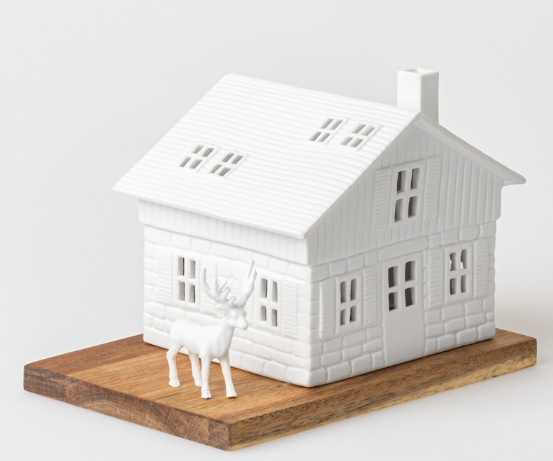 Lichthaus Skihütte: Weißes Keramikhaus mit Fensteröffnungen und kleinem Reh auf Holzsockel.