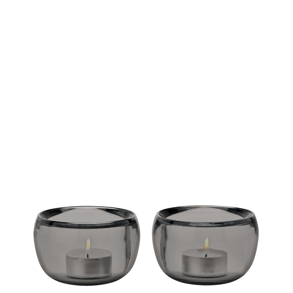 Zwei graue Ora Teelichthalter von Stelton mit brennenden Teelichtern, stimmungsvolle Dekoration für Zuhause.