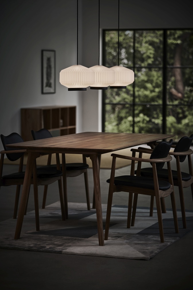 Esszimmer mit Shibui Pendelleuchte von Le Klint: Hängeleuchte mit plissiertem Lampenschirm über Holztisch.