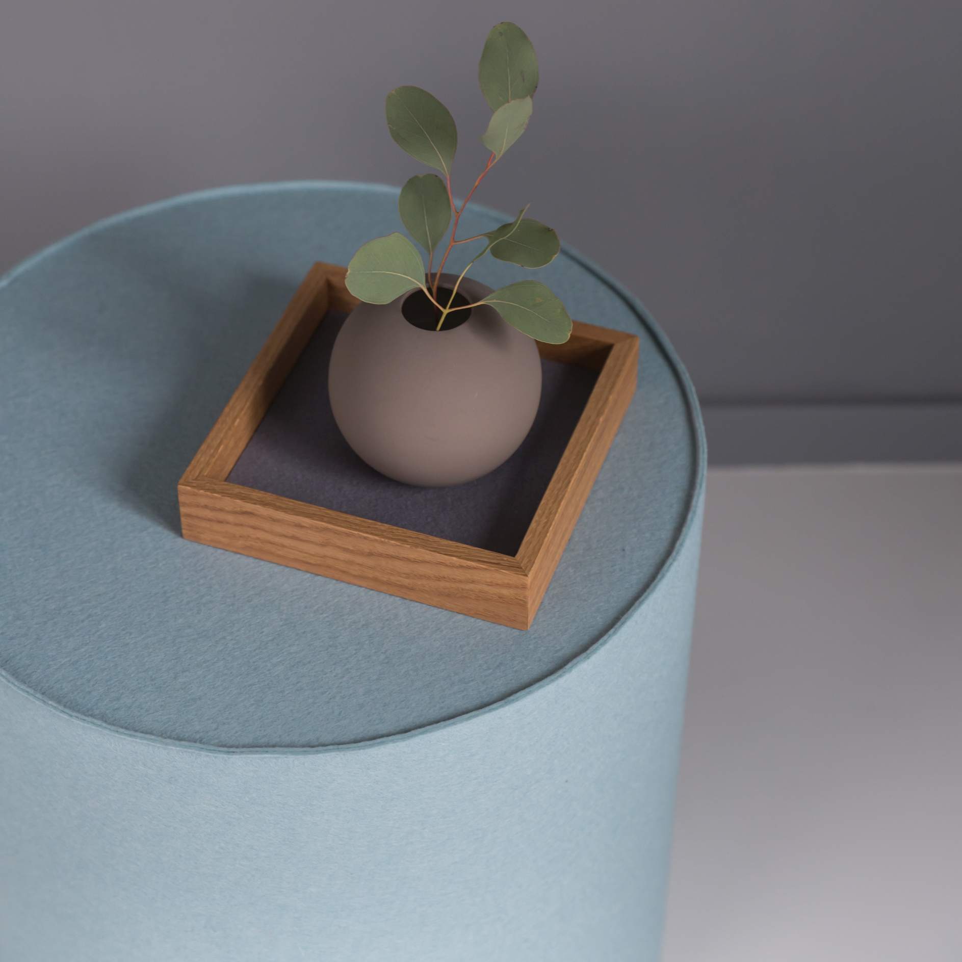 Blauer Rondo Hocker von Hey Sign mit Vase und Holztablett als Sitzmöbel und Ablage.