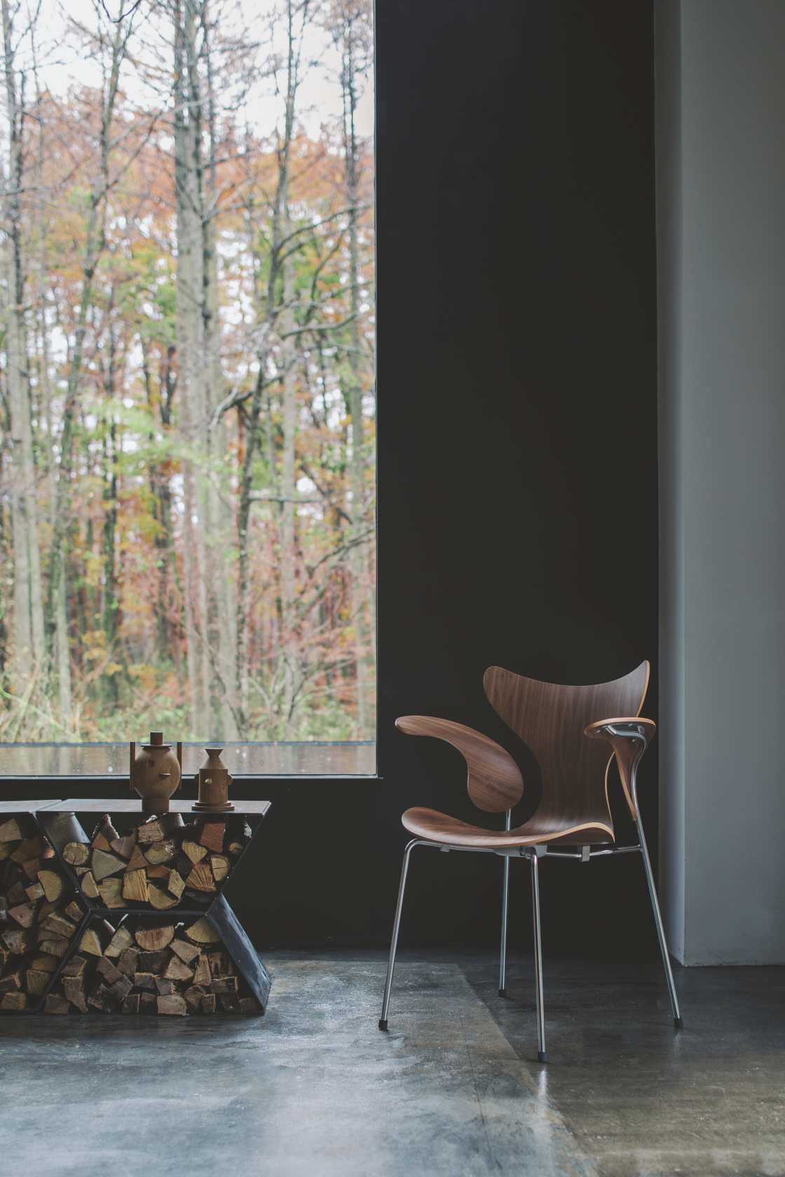 Fritz Hansen Lily Armlehnenstuhl 3208 aus Holz mit Stahlbeinen vor Fenster. Designklassiker.