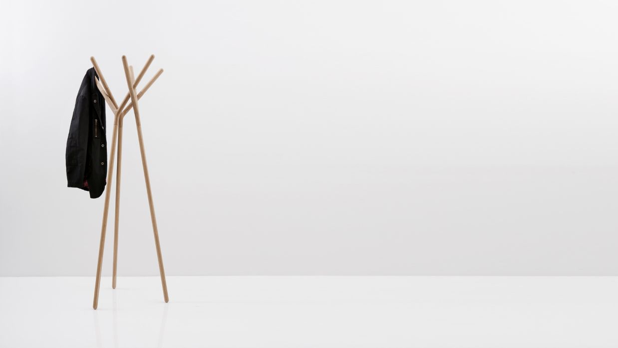 Game of Trust Garderobenständer von Miniforms aus hellem Holz mit einer schwarzen Jacke.