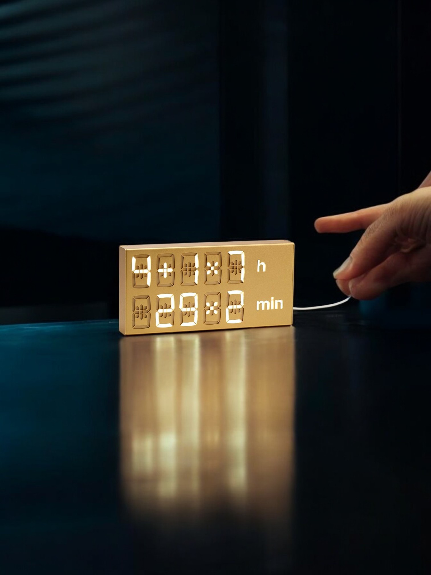 Goldene Flip-Clock Digitaluhr zeigt 4:29 Uhr, mit Hand im Hintergrund. Moderne Tischuhr für Wohnzimmer.