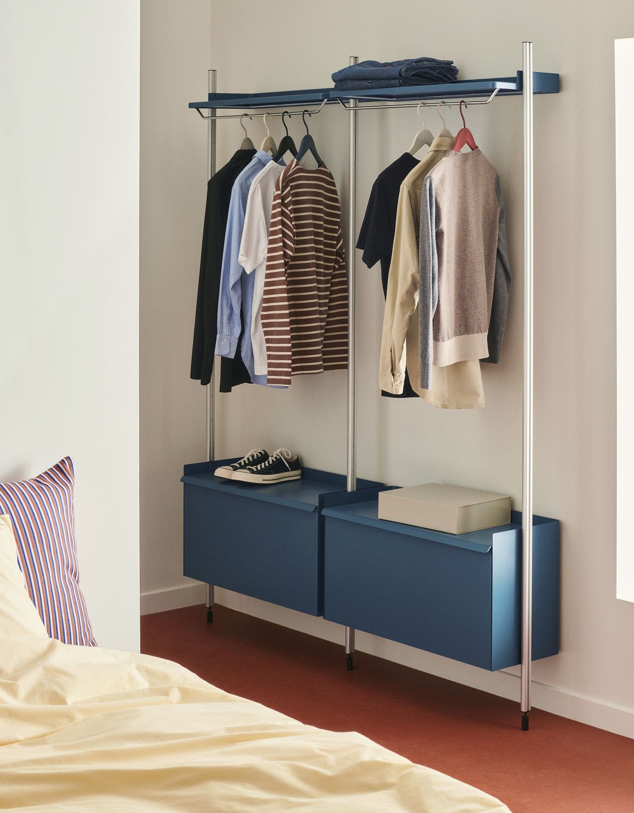Hay Pier System Regal mit Kleidung und blauen Schränken im Schlafzimmer. Garderobenlösung für moderne Einrichtung.