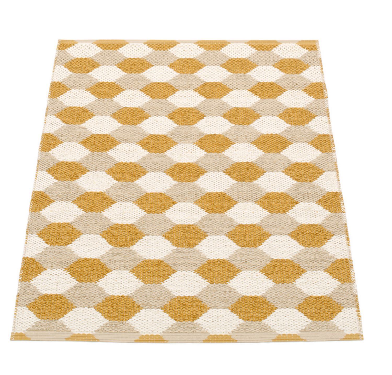 Dana Kunststoffteppich 70x100 cm von Pappelina mit ockerfarbenem und weißem Rautenmuster. Strapazierfähiger Teppich für Innen.